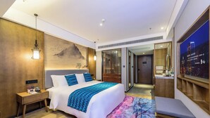 Una habitación de hotel moderna con una cama grande, una mesita de noche y un televisor en la pared.