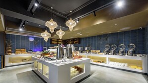 Un interior moderno con un mostrador central que exhibe diversos objetos, estanterías con utensilios de cocina e iluminación decorativa.