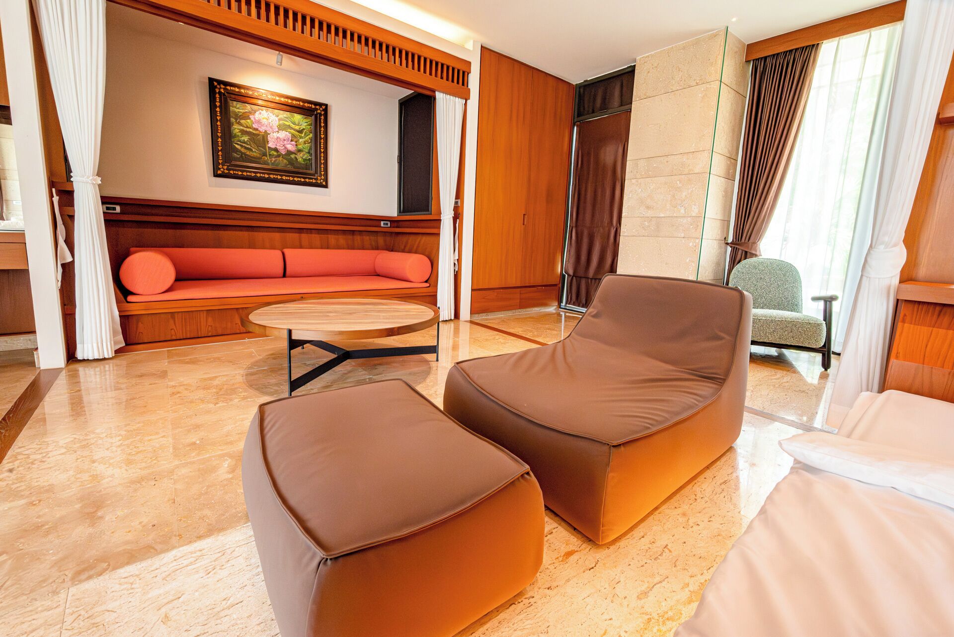 Una habitación de hotel moderna con un banco de madera, una mesa redonda y una silla acolchada.