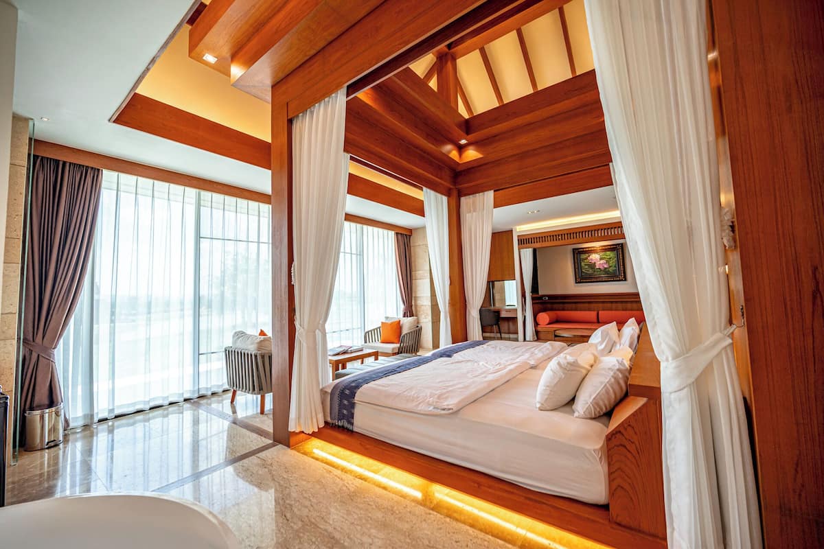 A spacious bedroom with a large bed, a desk, and a view of the outdoors.