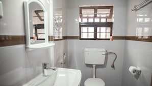 Une petite salle de bain avec un lavabo blanc, des toilettes et une fenêtre avec des barreaux.