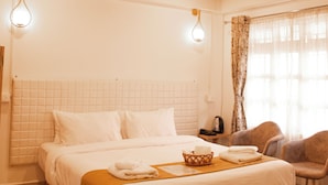 Une chambre à coucher avec un lit en bois, du linge de lit blanc, une table de chevet, une lampe et une chaise.