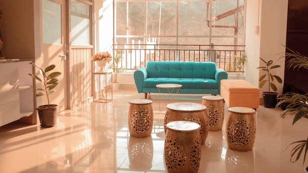 Une pièce spacieuse avec un canapé de couleur turquoise, une petite table ronde et des tabourets en bois décoratifs.