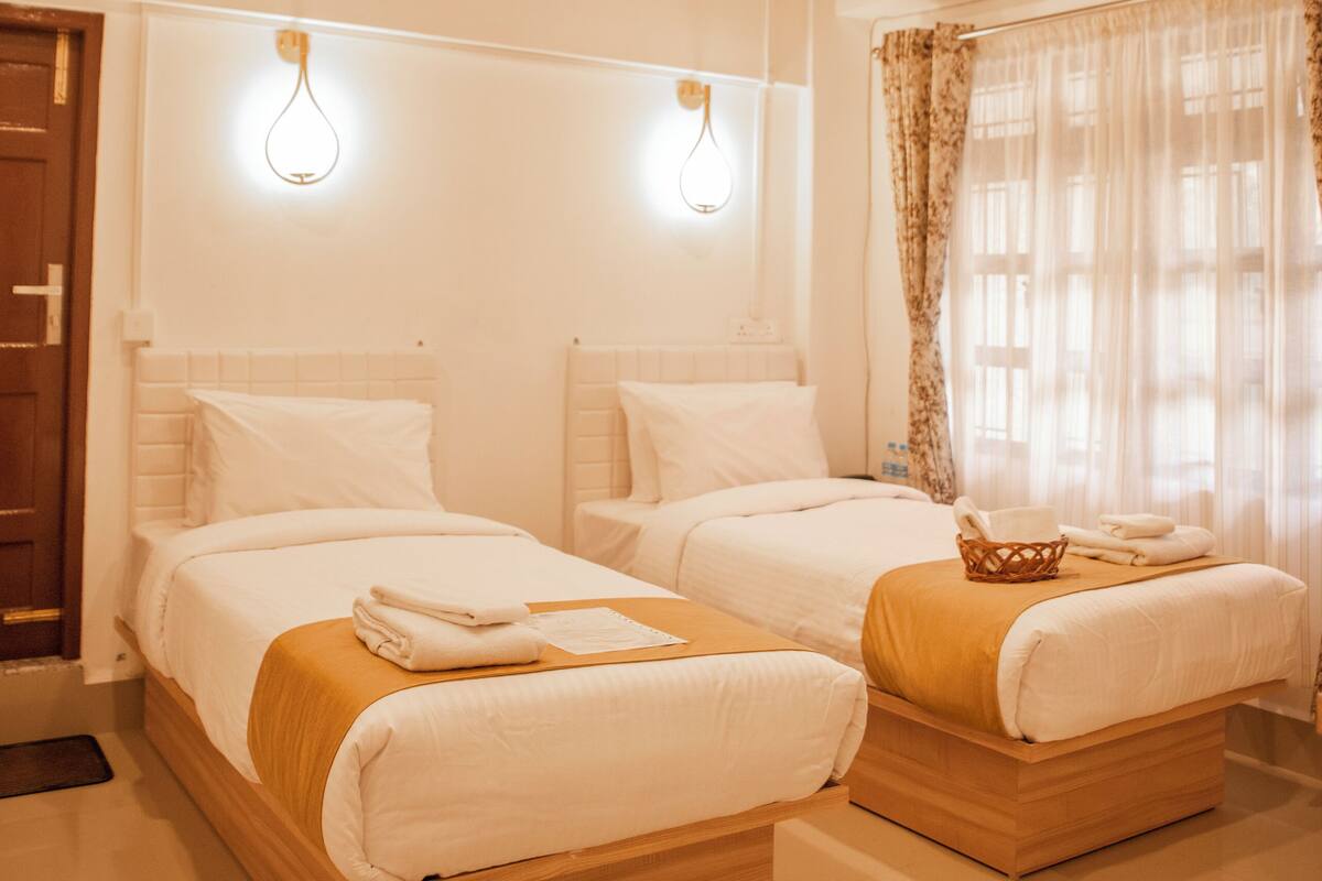A hotel room with two beds, wooden headboards, and a wooden ceiling.