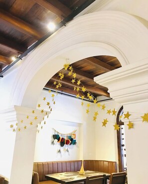A restaurant with a high arched ceiling, wooden beams, and a seating area with a long wooden bench and a table. - CELONESE HOTEL & RESTAURANT Kandy (Kandy)