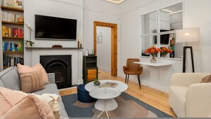 En moderne stue med pejs, et fladskærms-tv, en reol og et spiseområde med et bord og stole.