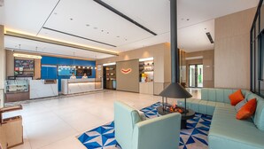 A modern hotel lobby with a reception desk, seating area, and a coffee shop. - Yishang Hotel (Zhanjiang)