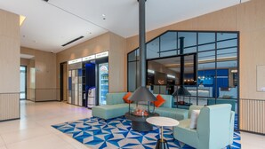 A modern lobby with a geometric patterned rug, a central seating area with a fire feature, and a reception desk. - Yishang Hotel (Zhanjiang)