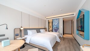 A modern hotel room with two beds, a round table, a desk, and a TV mounted on the wall. - Yishang Hotel (Zhanjiang)
