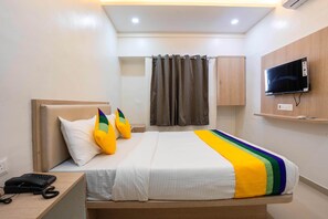 A hotel room with a bed, a TV mounted on the wall, a telephone on the side table, and a curtain. - Itsy Hotels Iconic (Pune)