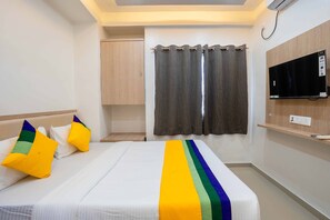 Une chambre d’hôtel avec un lit, une télévision, une armoire et un rideau.