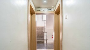 A hallway leading to a staircase with a fire extinguisher on the wall. - Itsy Hotels Iconic (Pune)