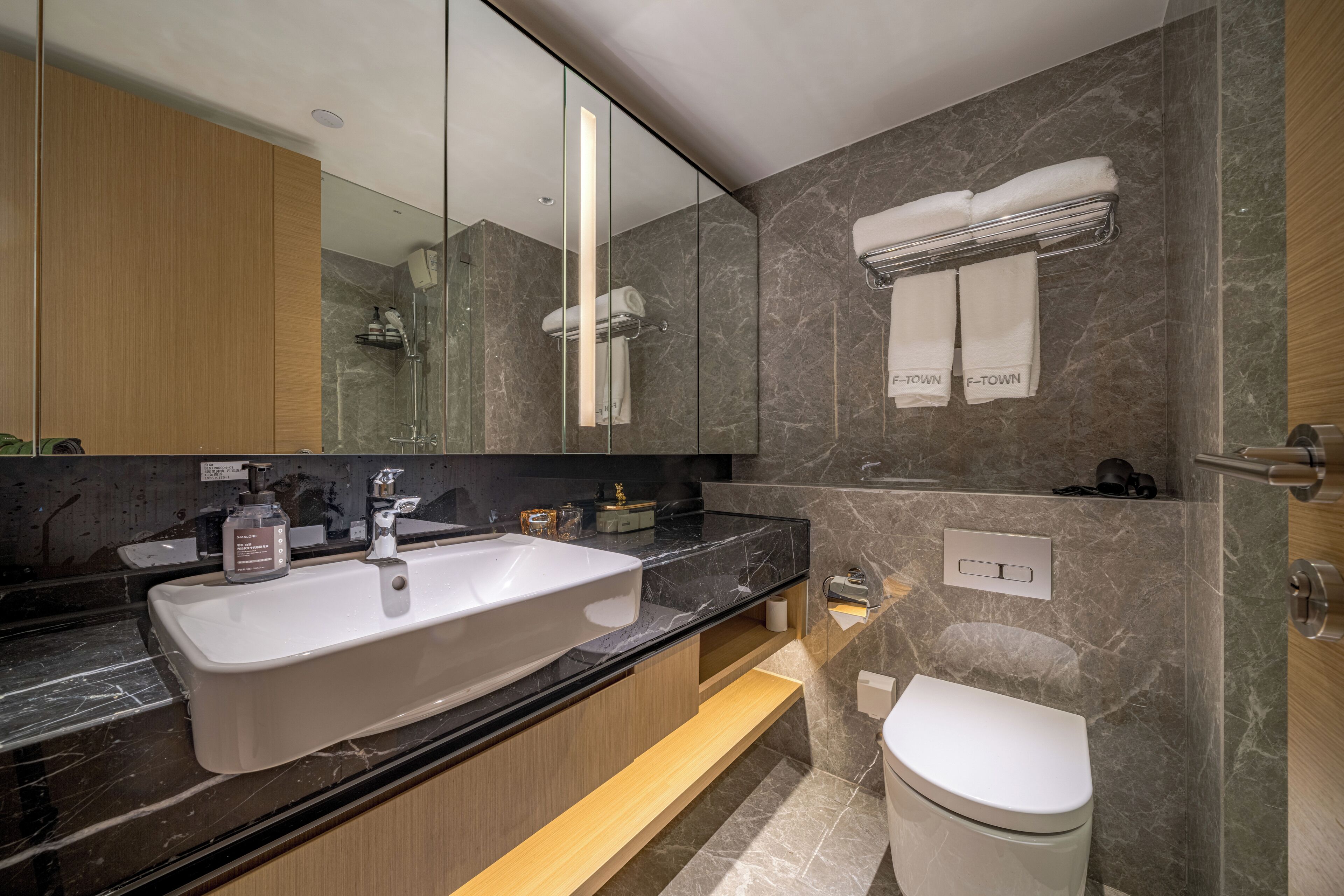 A modern bathroom with a large sink, a toilet, and a mirror.