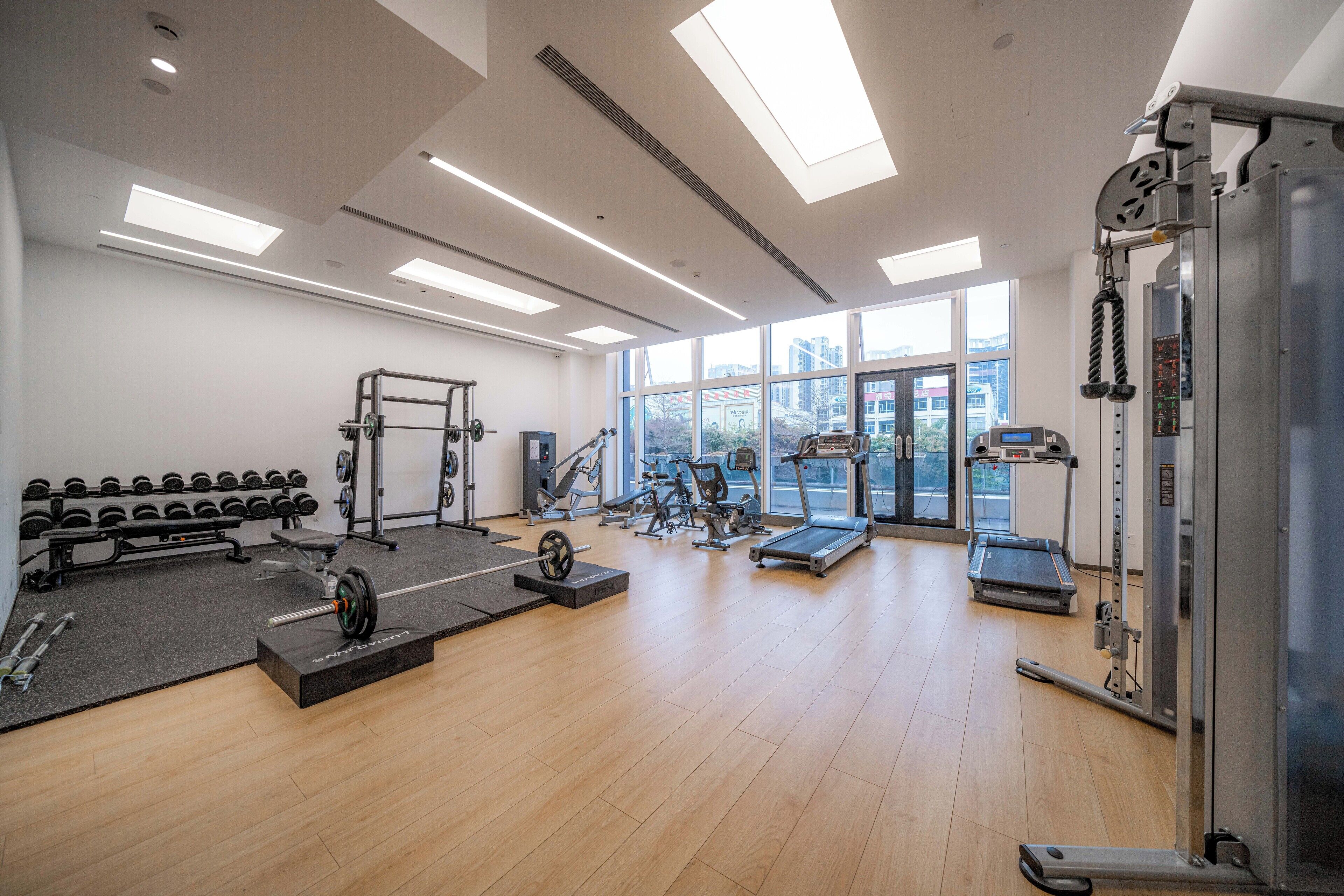 Un gimnasio con varios equipos de ejercicio, incluyendo pesas, una banca y máquinas de cardio.