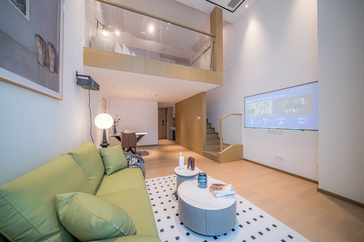 A modern living room with a green sofa, a round coffee table, and a projection screen on the wall.