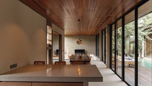 A modern dining area with a long table, wooden ceiling, and large windows overlooking a pool. - The Akasha Canggu Luxury Villas (Canggu)