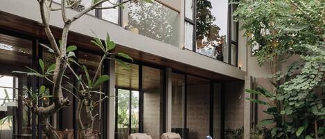 Una casa moderna con piscina, dos sillones de descanso y un árbol.