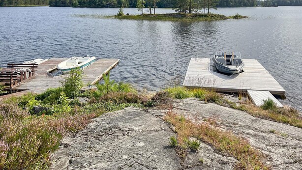 Une jetée au bord du lac avec deux bateaux, une plateforme en bois et une rive rocheuse.