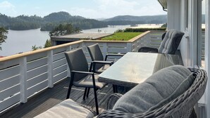 Een terras met tuinmeubilair met uitzicht op een meer en heuvels.