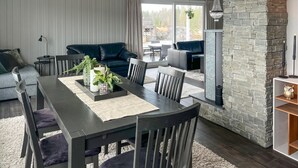 Een moderne woonkamer met een donker houten eettafel, beklede stoelen en een accentmuur van steen.