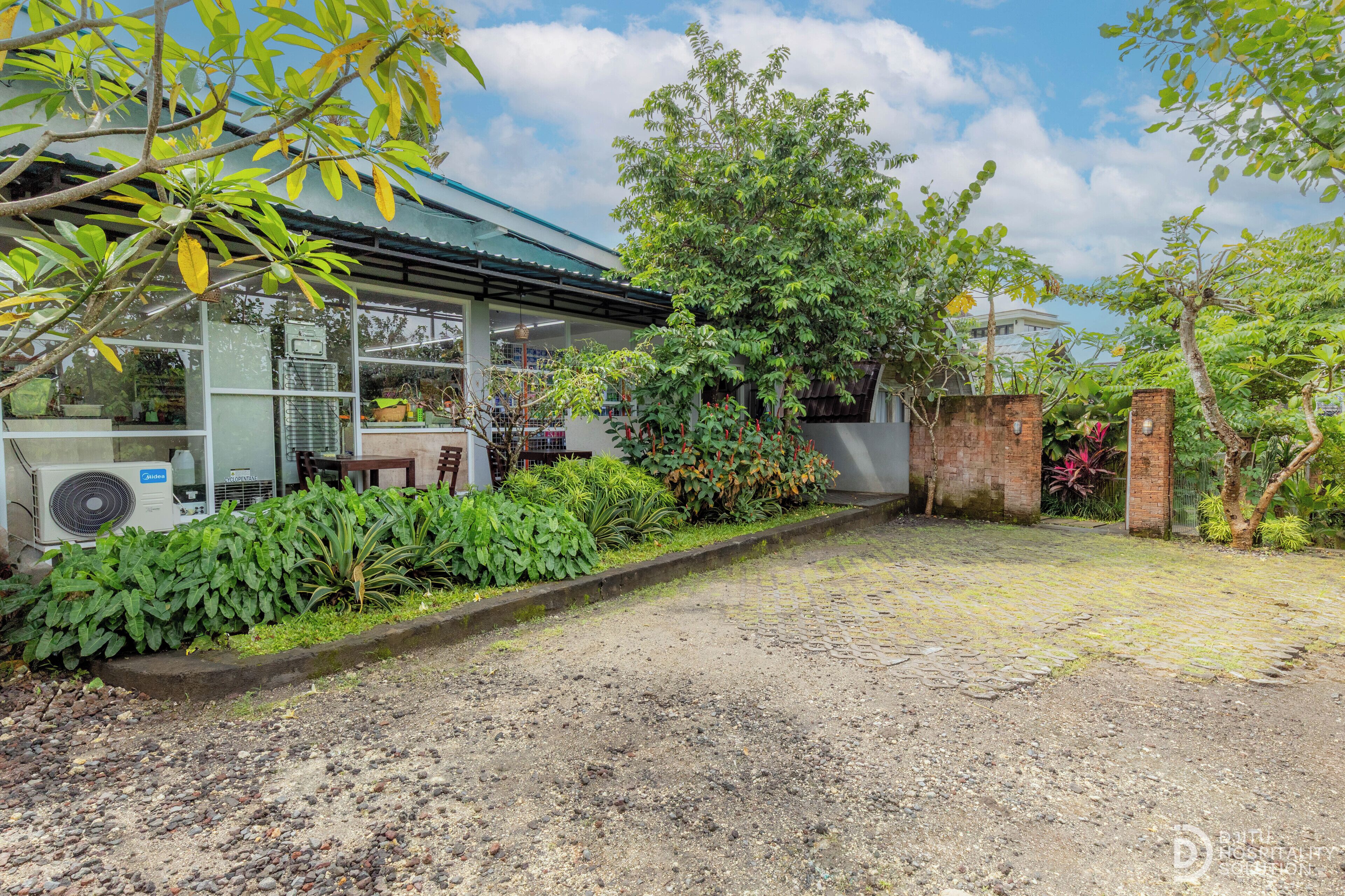 A house with a covered porch, a brick wall, and a gravel driveway.