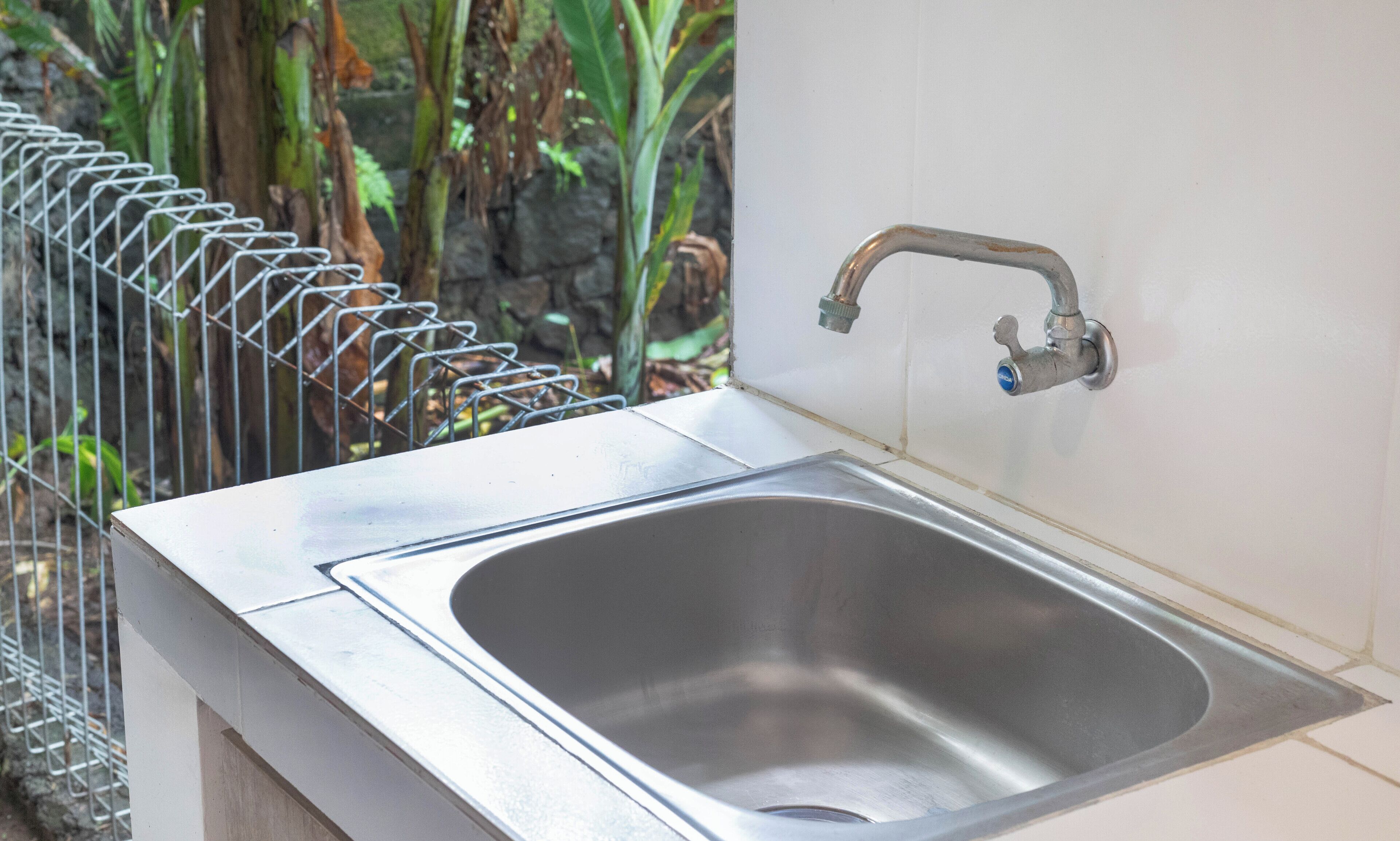 A stainless steel sink with a single faucet, mounted on a white countertop.