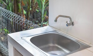 A stainless steel sink with a single faucet, mounted on a white countertop. - Double A View (Pererenan)