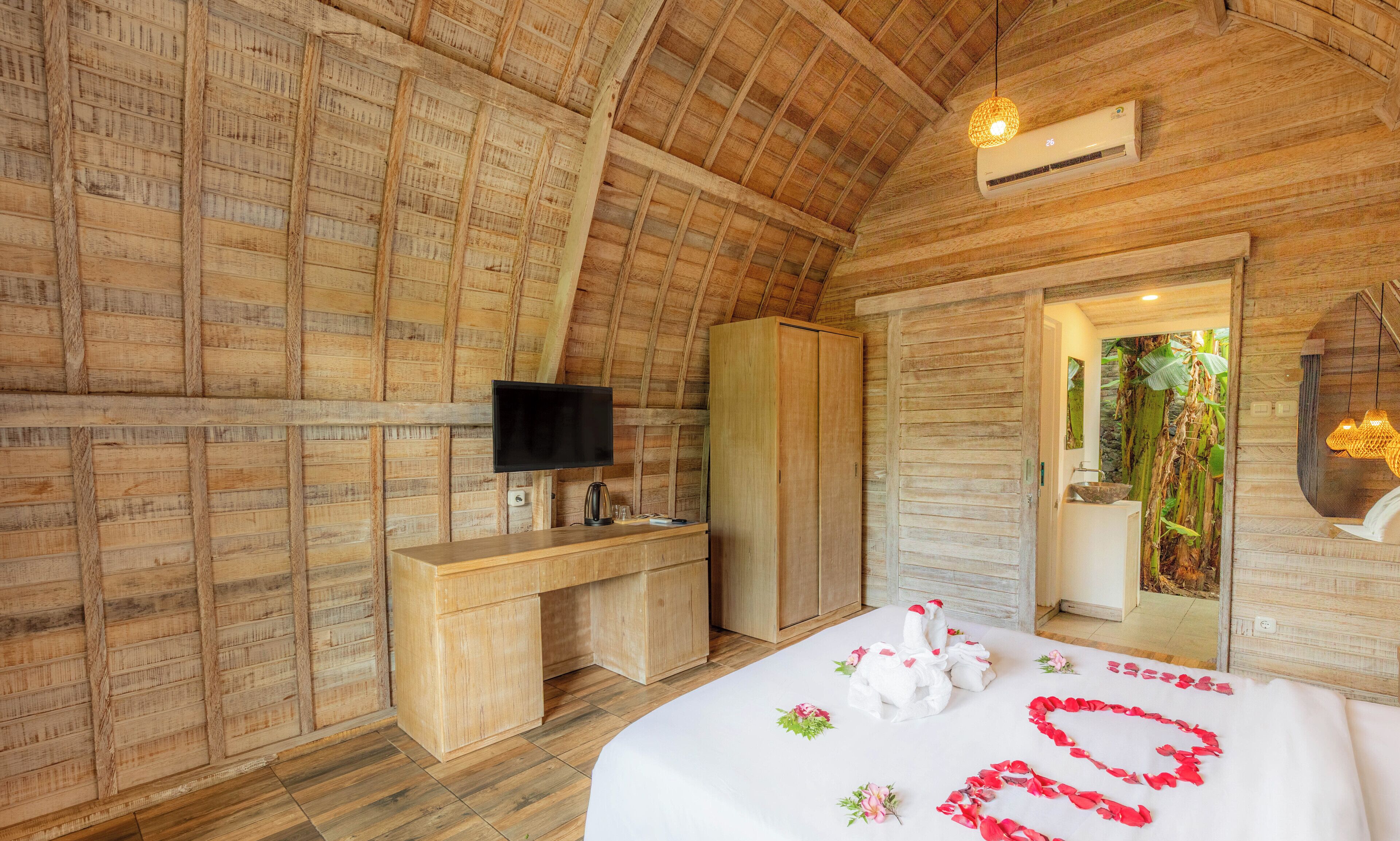 Una habitación de madera con una cama, un escritorio, un televisor y un armario.