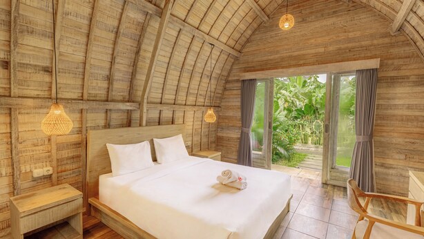 A spacious bedroom with a large bed, wooden ceiling, and a view of greenery outside. - Double A View (Pererenan)