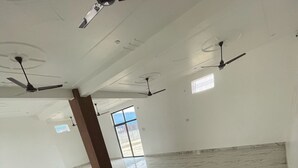 Une pièce spacieuse dotée d’un sol en marbre et de plusieurs ventilateurs de plafond.