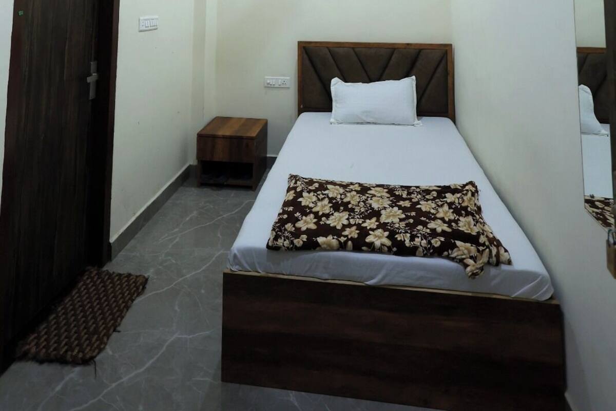 A bedroom with a bed, a ceiling fan, a wooden door, and a small bedside table.