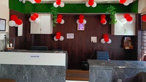 A reception area with marble counters, a ceiling fan, and red and white balloons. - Shri Girraj Residency (Mathura)