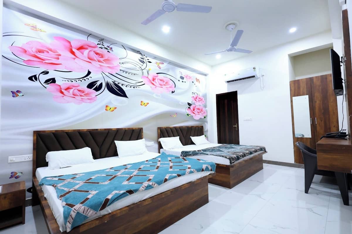 A hotel room with two beds, a wooden headboard, a large floral mural, a ceiling fan, and an air conditioning unit.