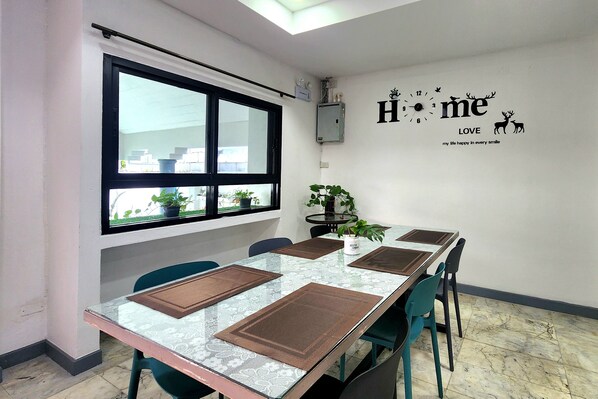 A conference room with a glass table, chairs, and a large window. - HomeyMaeKha Hostel Chiangmai (Chiang Mai)