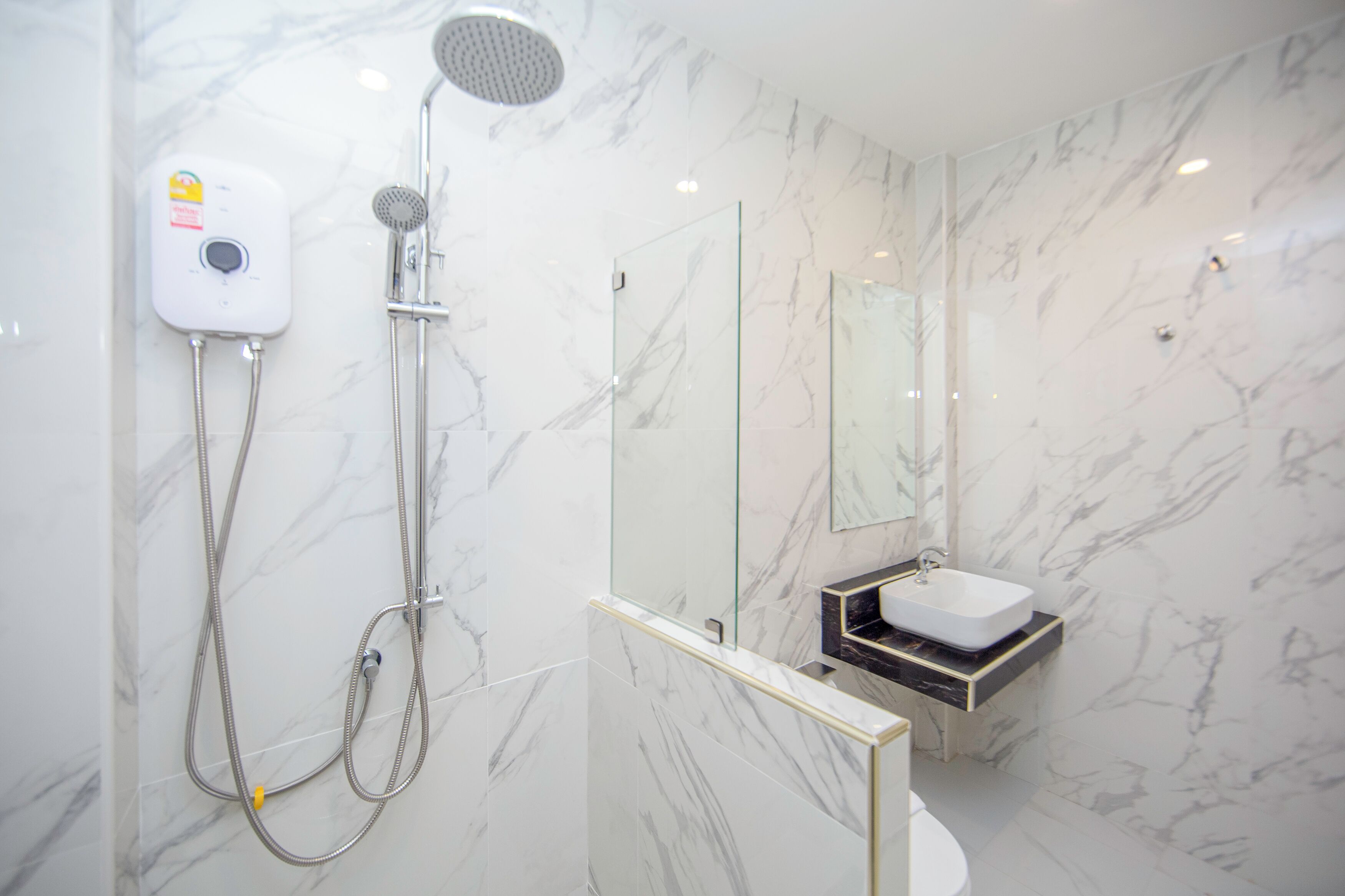 A modern bathroom with a glass-enclosed shower, a white sink, and marble walls.