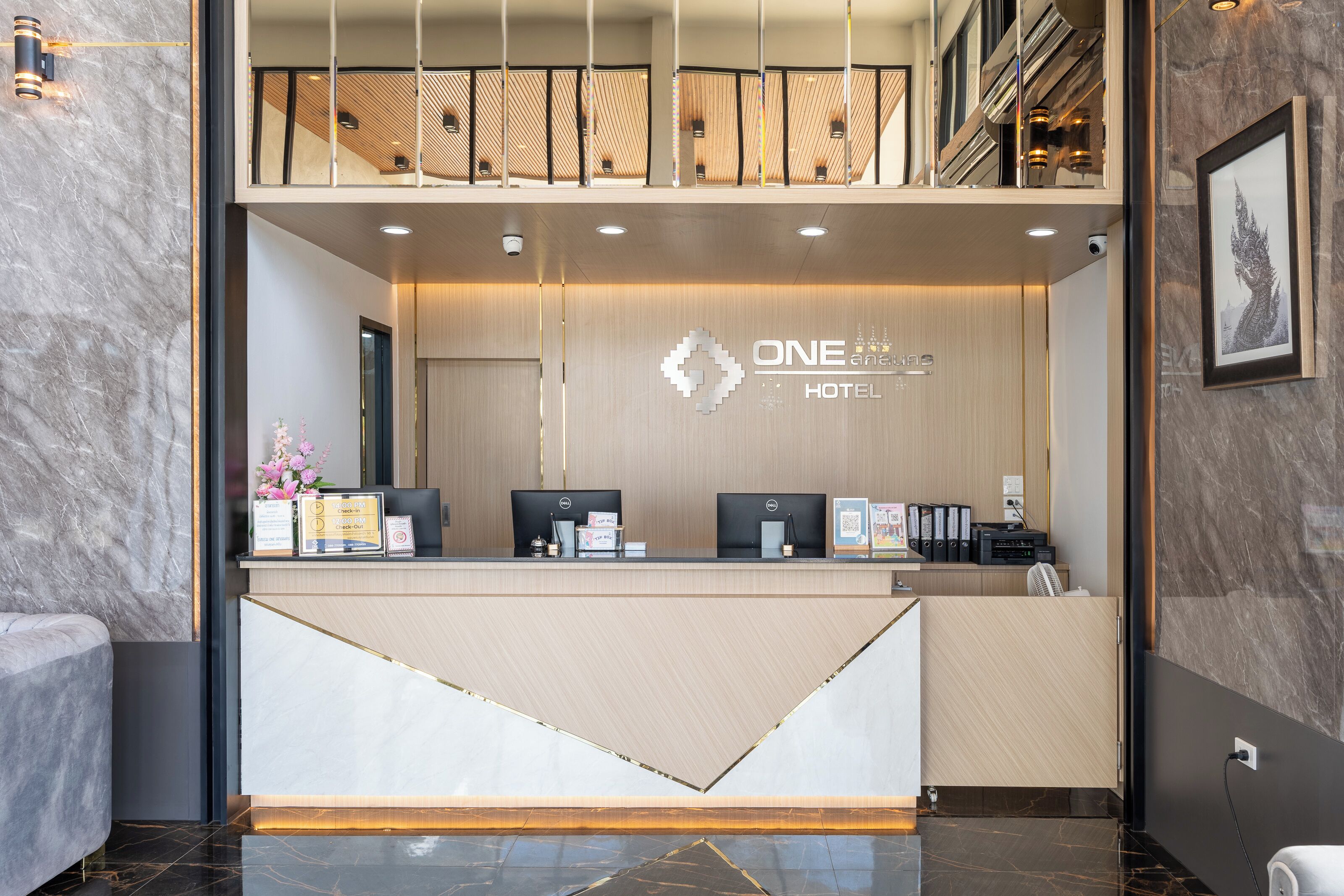 Una reception hotel dal design moderno, con un logo, computer e un quadro appeso al muro.
