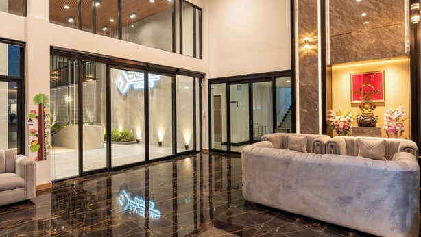 Een ruime lobby met een comfortabele bank, een receptiebalie en een grote glazen deur naar de ingang.