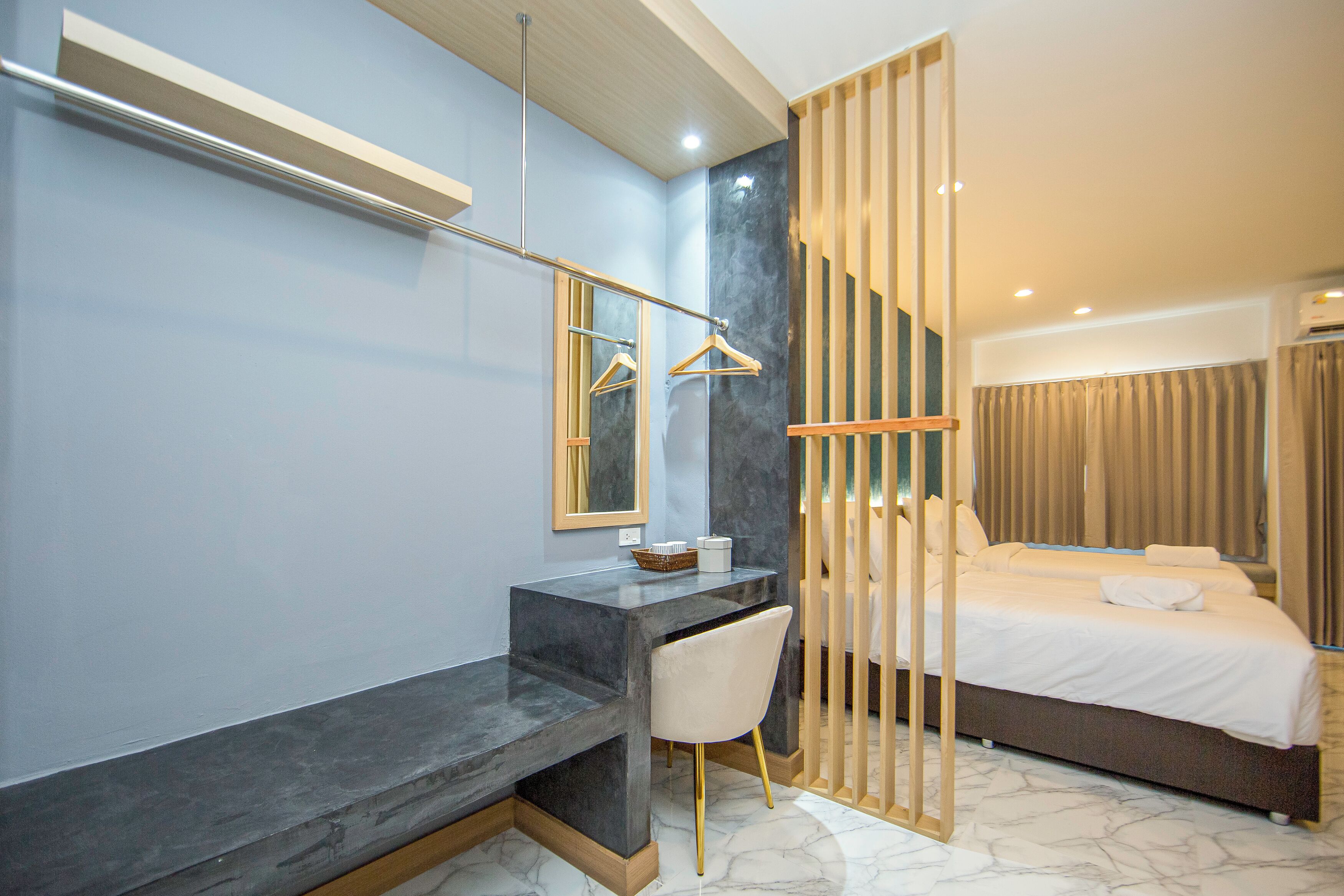 A modern hotel room with a marble floor, a bed with white linens, a desk with a chair, and a mirror with a wooden hanger.