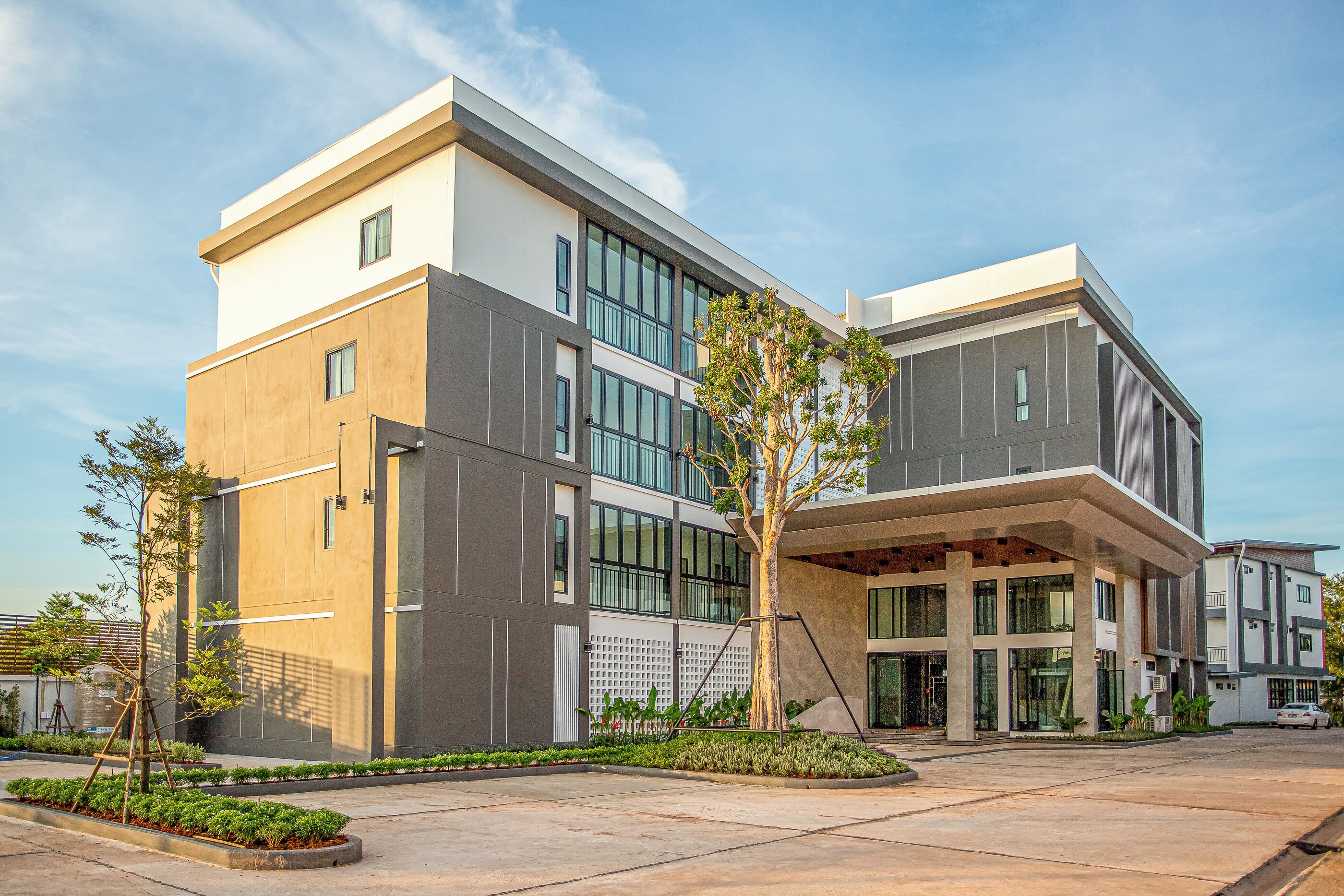 A modern building with a flat roof, large windows, and a central courtyard with a tree.