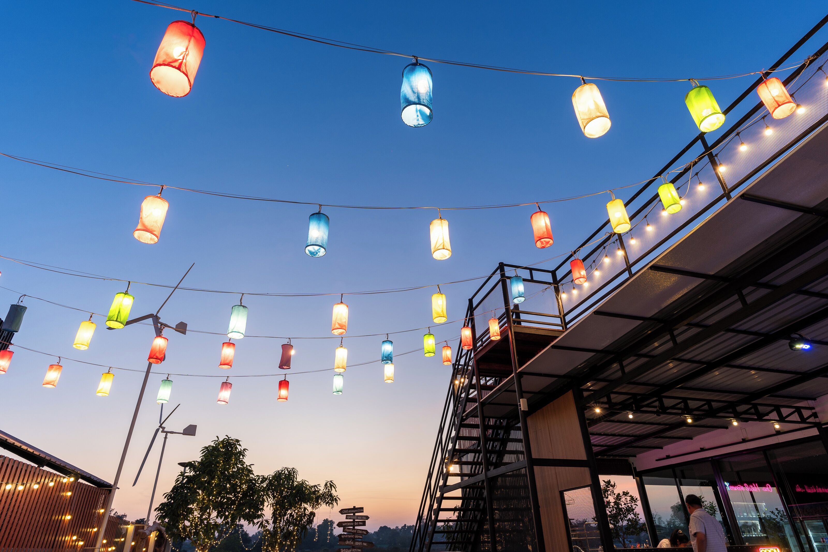 A building with a metal staircase and a string of colorful hanging lights.