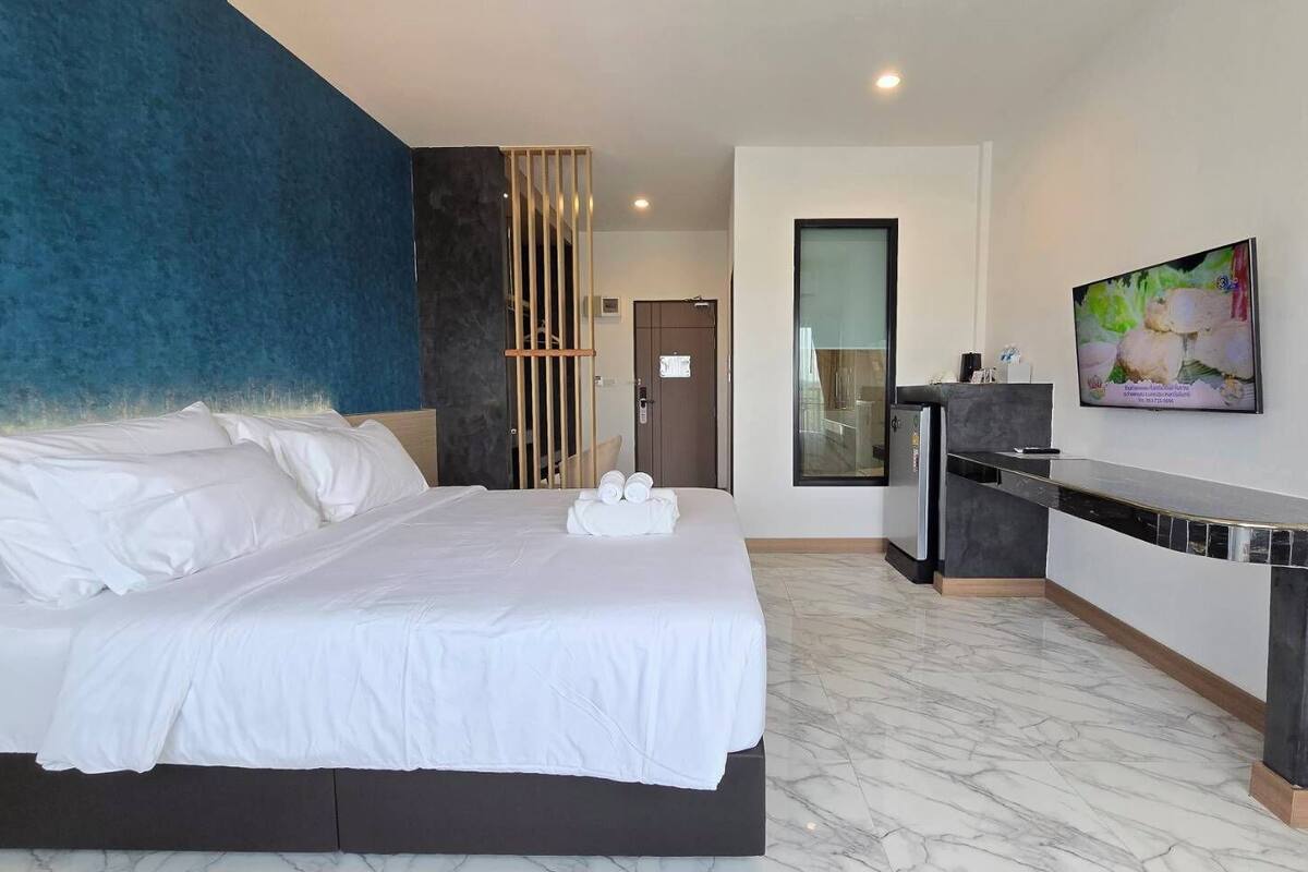Ein modernes Hotelzimmer mit einem großen Bett, einem Schreibtisch und einem Fernseher.