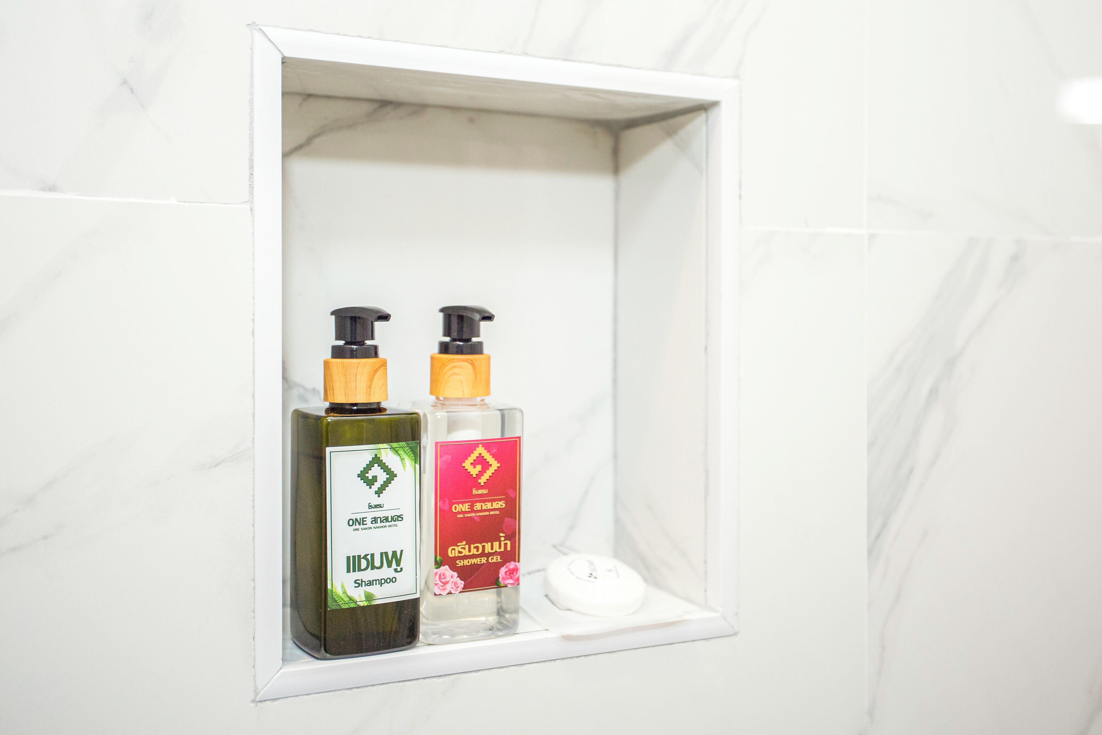 Una repisa de baño con dos botellas de champú y una de gel de ducha.