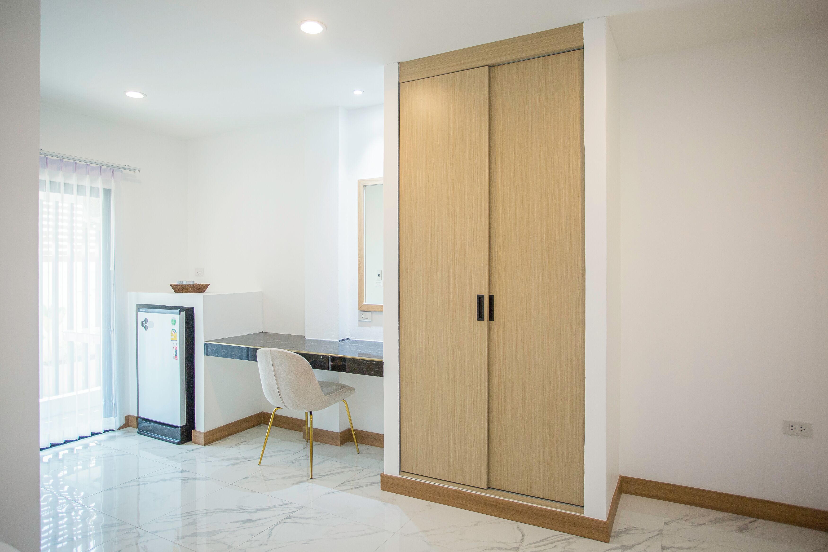 A modern kitchen with a refrigerator, a dining area with a chair, and a large wooden wardrobe.