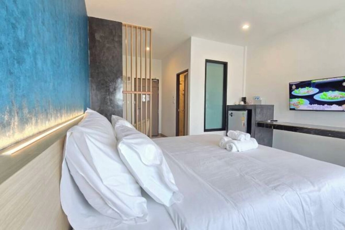 Une chambre d’hôtel avec un grand lit, un téléviseur fixé au mur et un décor mural en panneaux de bois.