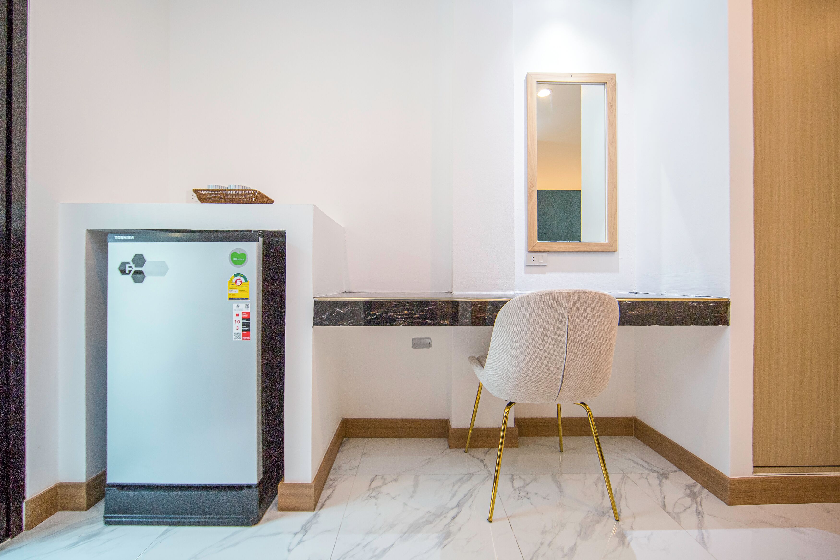 A compact kitchen with a refrigerator, a chair, a countertop, and a mirror.