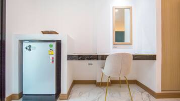 A compact kitchen with a refrigerator, a chair, a countertop, and a mirror.