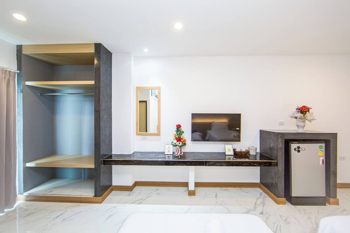 Ein Hotelzimmer mit Marmorboden, einer schwarzen Arbeitsplatte, einem kleinen Kühlschrank, einem Fernseher und einem Spiegel.