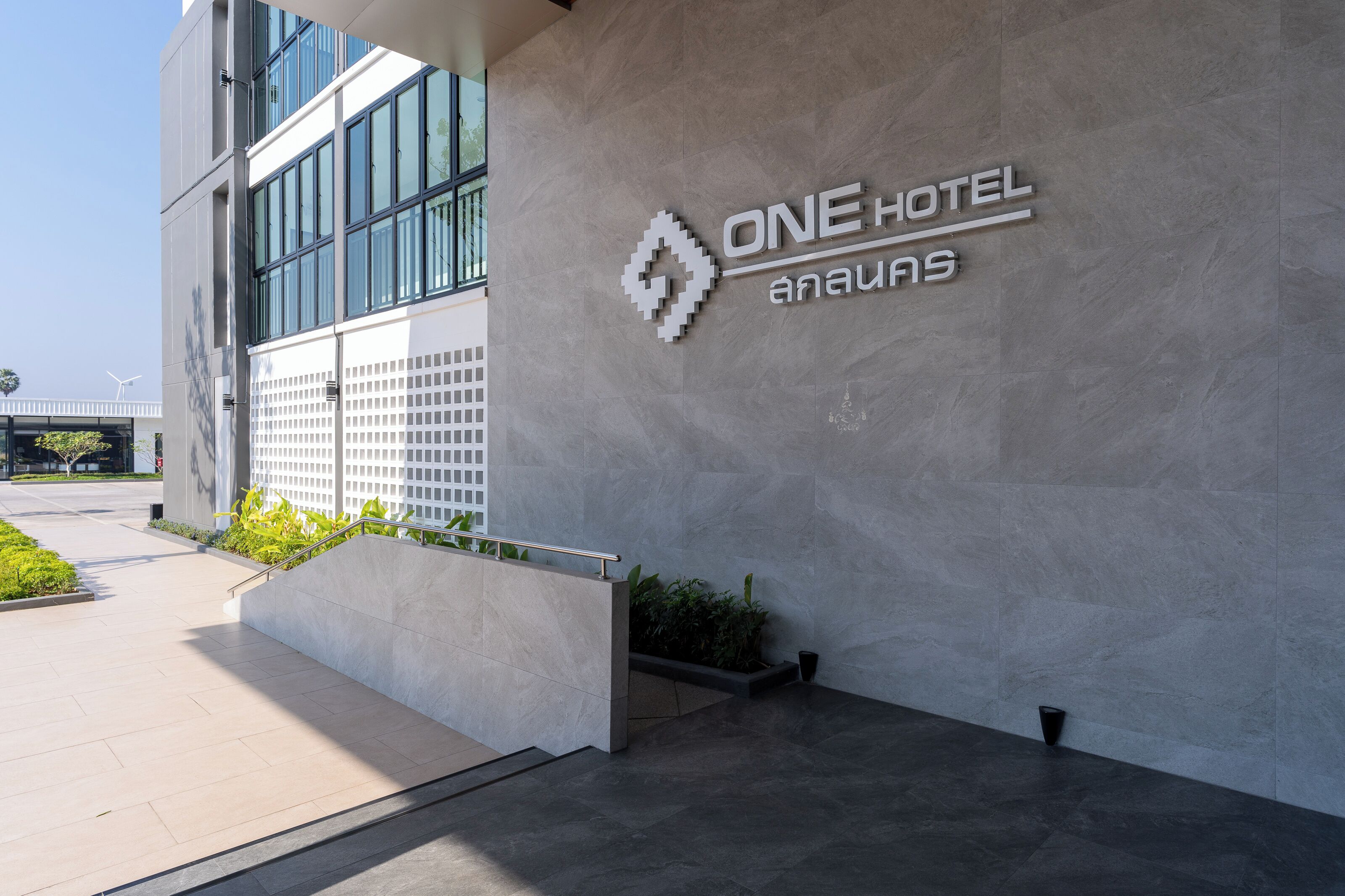 Une entrée d’hôtel moderne, avec une enseigne bien visible indiquant « ONE HOTEL ».