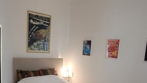 Makuuhuone, jossa on sänky, kattotuuletin, puulattia ja seinäkoristeita.