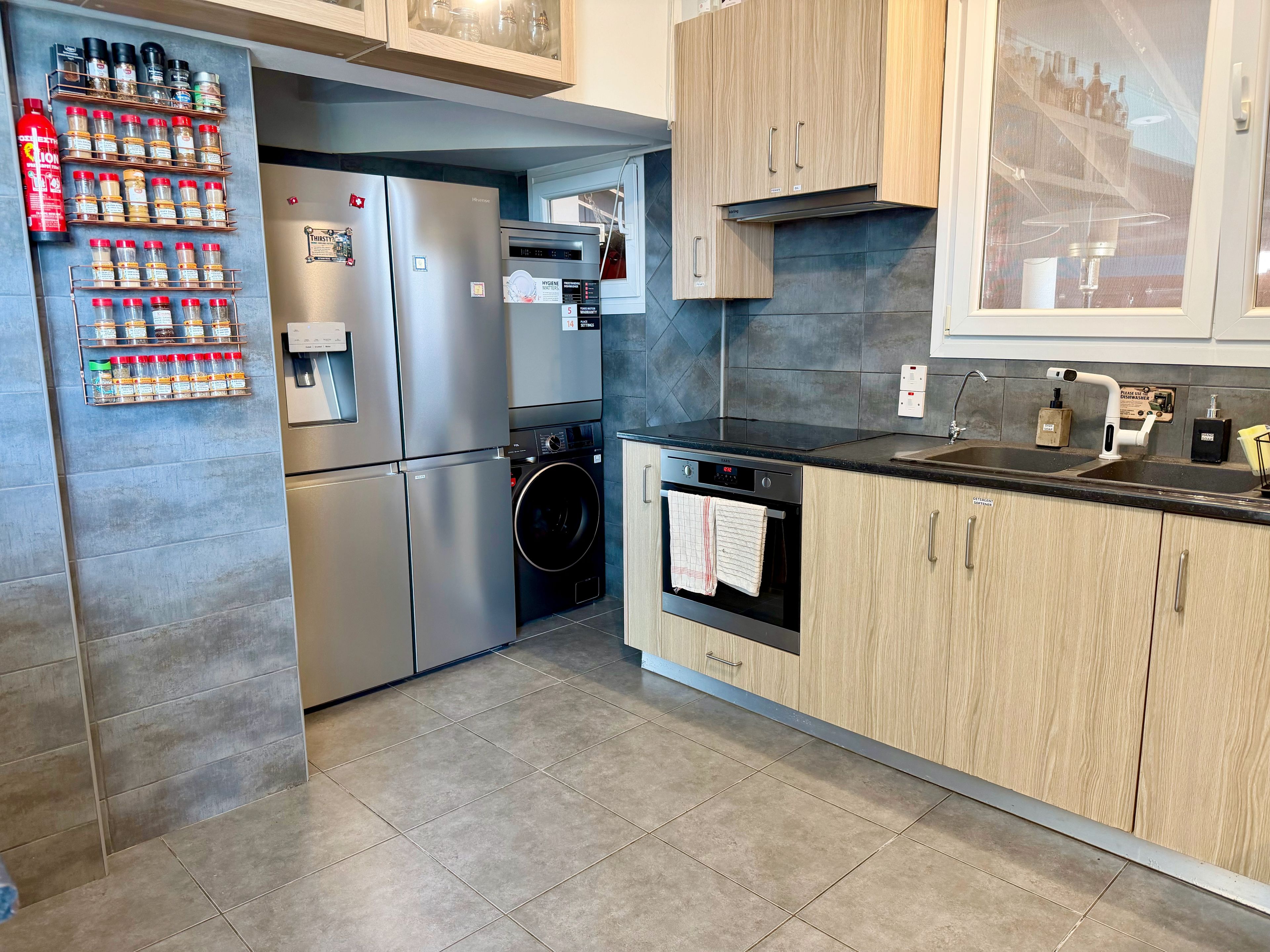 A modern kitchen with stainless steel appliances, a built-in washing machine, and a black countertop.